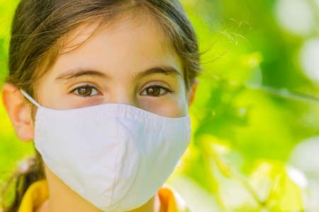 Little girl with mask against corona virus covid outdoorの写真素材