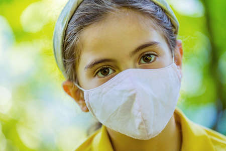 Little girl with mask against corona virus covid outdoorの写真素材