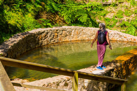 Sao Miguel, Azores island, Portugal: Woman watching the steam from Hot springs and fumaroles at the...