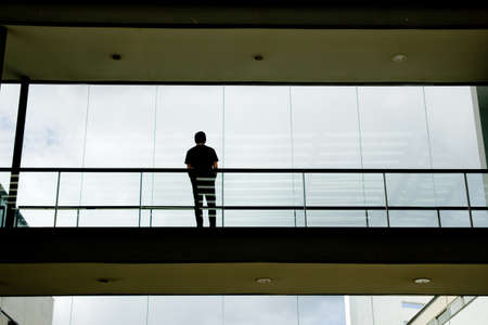 Silhouette view of young businessman in a modern office building interior with panoramic windows.の写真素材