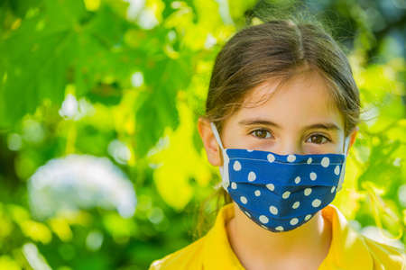 Little girl with mask against corona virus covid outdoorの写真素材