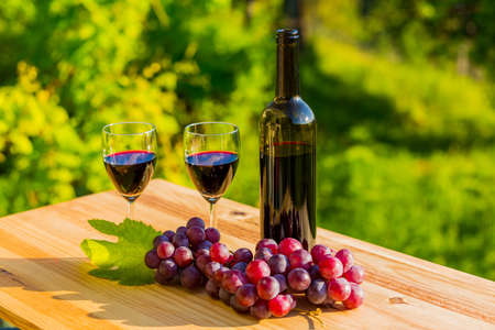 wine bottle and grapes on wooden table, outdoorの写真素材