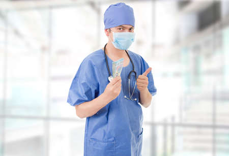 Happy male doctor holding bank notes, at the hospitalの写真素材
