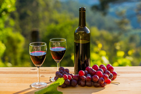 wine bottle and grapes on wooden table, outdoorの写真素材