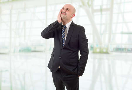 Businessman in a suit gestures with a headache, at the officeの写真素材