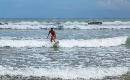 Bali, Indonesia: Surfer man on a sandy beach with a surfboard. Beach, sea, bright sunny day. Summer lifestyleのeditorial素材