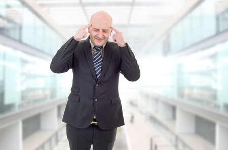 Businessman in a suit gestures with a headache, at the officeの写真素材