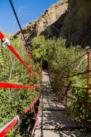 Long old wooden walking swing bridge over river in Los Cahorros Granada, Spainの写真素材