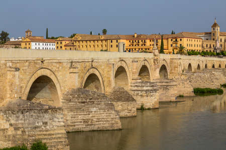 Cordoba, Spain: People walk on the Roman Bridge of Cordoba, a stone bridge that spans river Guadalquivirの写真素材