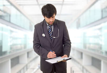 male doctor thinking with his notes, at the hospitalの写真素材