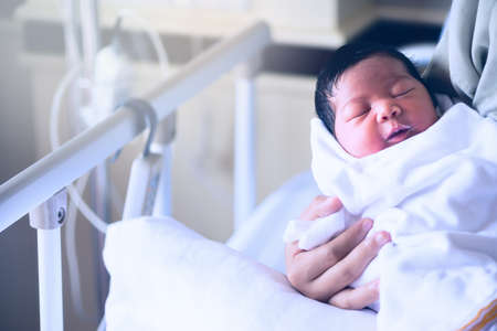 An infant was fed by her mom. She was yawning while drinking a bowl of milk in the same time.の写真素材