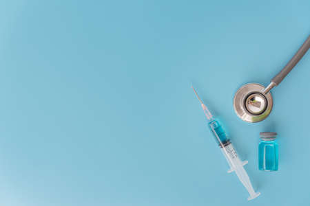 A syringe with liquid vaccines on blue