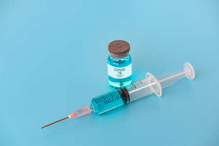 A syringe with liquid vaccines on blue