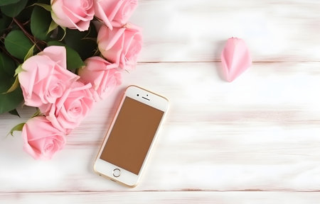 beautiful rose flowers and phone on light wooden table for freelancing business card decorの素材