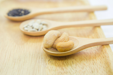 sunflower kernels and black sesame and cashew nuts on spoonの写真素材