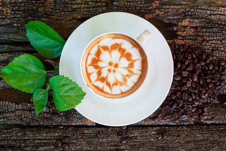 hot cappuccino on wood table /hot cappuccino with coffee bean and green leaf on wood tableの写真素材