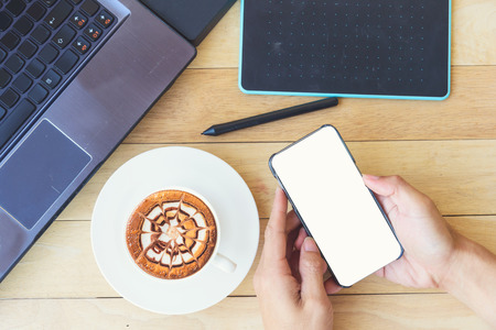 hot cappuccino with nice milk pattern and smart phone on work space table in office