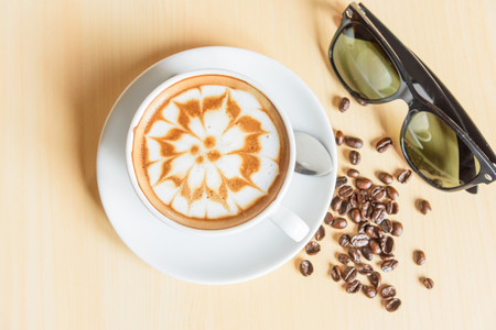 hot cappuccino with nice milk pattern with coffee bean and sunglassの写真素材