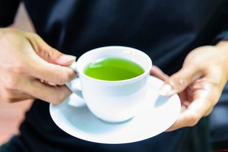 The man hold the hot green tea on his hand before drink / hot matcha