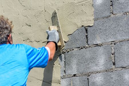 Worker plaster the cement wall in construction site