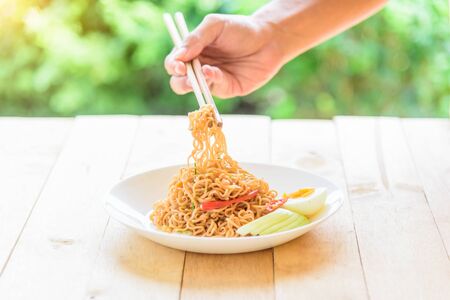 The man use chopstick clamp fried noodles from the dishの写真素材