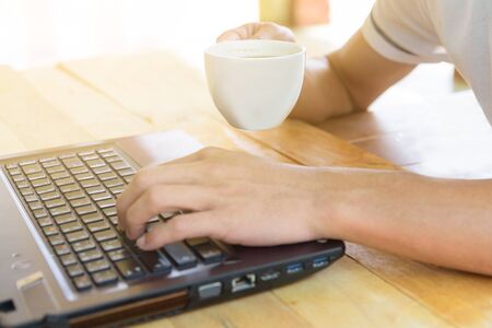 Work from home / The man use laptop and have a cup of hot coffee in working timeの写真素材
