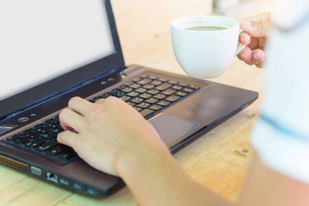 Work from home / The man use laptop and have a cup of hot coffee in working timeの写真素材