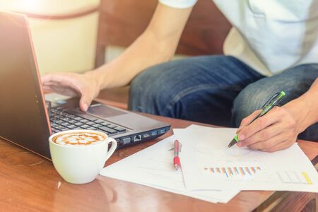 Work from home / The man use laptop and have a cup of hot coffee in working timeの写真素材