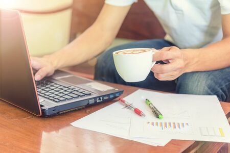 Work from home with hot coffee on the table / hot coffee with laptop on work spaceの写真素材