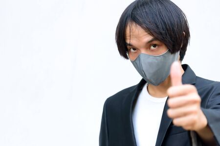 A asian man wear mask and show his hand thump upの写真素材