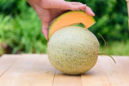 The man use knife split the orange melon on wood plateの写真素材