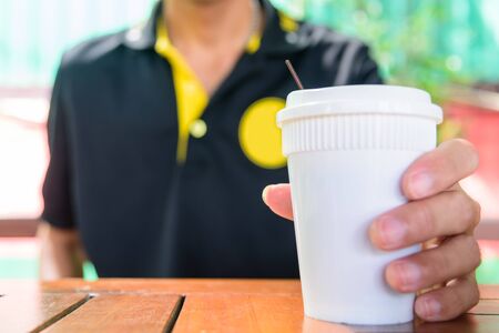 The man hold Paper cup of hot coffee for drinkの写真素材