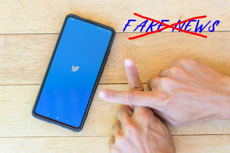 Bangkok, Thailand - 25  August, 2020 : Loading logo of twitter with finger cross sign for anti fake newsのeditorial素材