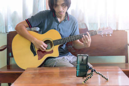 The man live traing the guitar practice streaming by smartphoneの写真素材