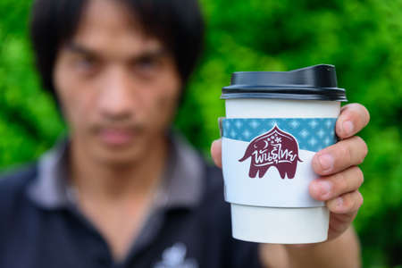 Bangkok,Thailand - 6 April, 2021: The man hold the paper cup of Punthai coffeeのeditorial素材