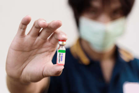 The man hold the Vaccine for treat the people infect with virus / COVID-19 vaccineの写真素材