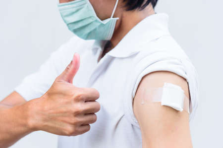 asian man get vaccinated and show his thumb up sign.の写真素材