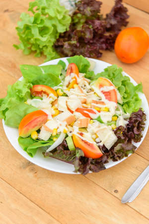 Mixed fresh vegetables salad in white dish on wood plateの写真素材