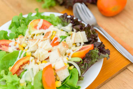 Mixed fresh vegetables salad in white dish on wood plateの写真素材