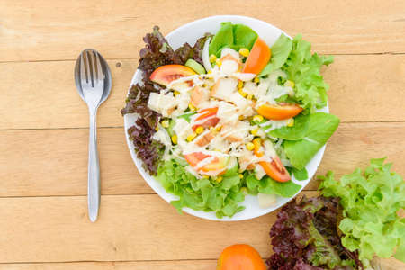 Mixed fresh vegetables salad in white dish on wood plateの写真素材
