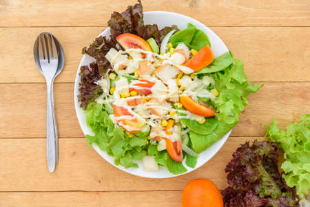 Mixed fresh vegetables salad in white dish on wood plateの写真素材
