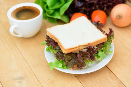 Sandwich tuna in white dish with hot coffee on tableの写真素材