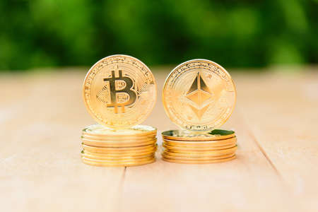 Closeup to Golden Bitcoin and ethereum cryptocurrency on the wood plateの写真素材