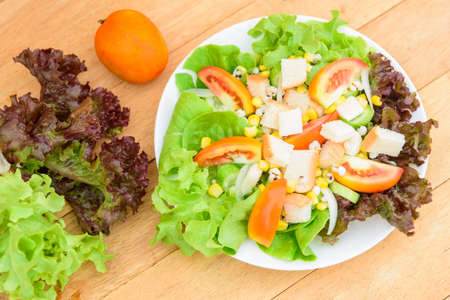 Mixed fresh vegetables salad in white dish on wood plateの写真素材