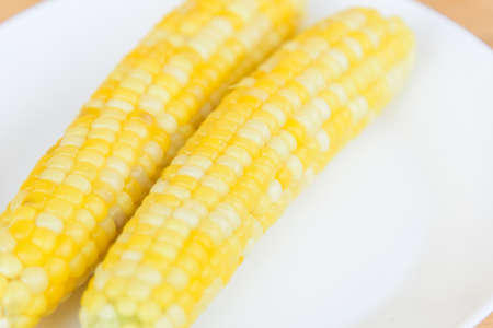 Closeup to white boiled corn on wood plateの写真素材