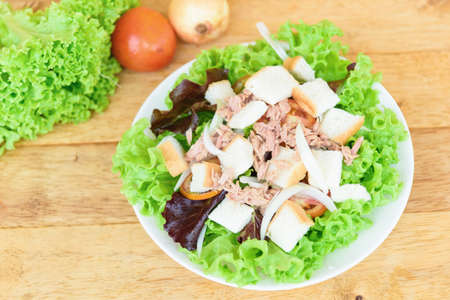 Closeup to tuna salad in the white dish on wood plateの写真素材