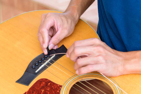 The musician replace the new guitar strings for his guitar