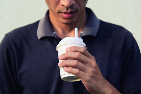 The man show the coffee paper cup to you - hot coffee for youの写真素材