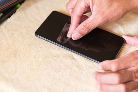 cleaning mobile phone screen by adhesive clear tape. Before apply the smart phone screen protect flimの写真素材