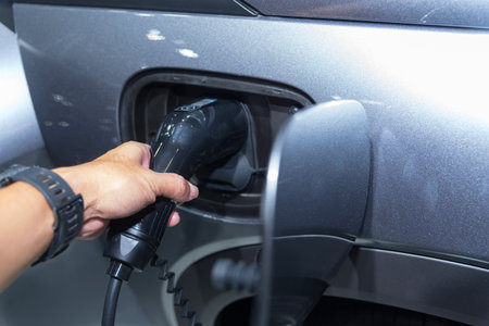 Charging an electric car, closeup of a man's hand